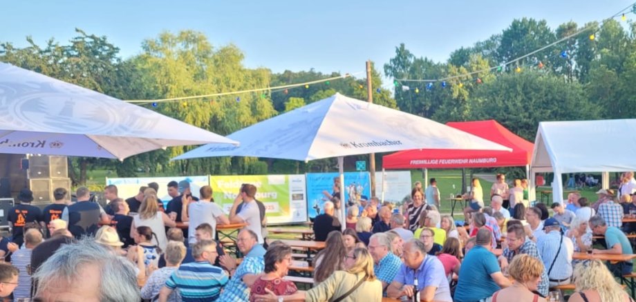 Personen Bierzeltbänke Sonnenschirme HImmel Bäume Lichterkette