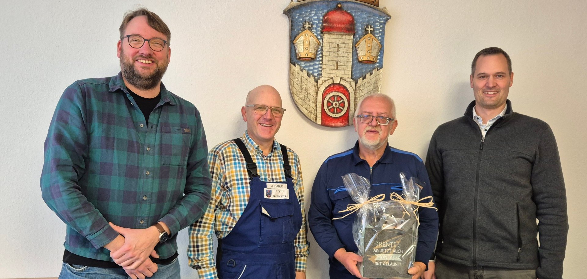 Personen stehen vor einer Wand mit einem Stadtwappen