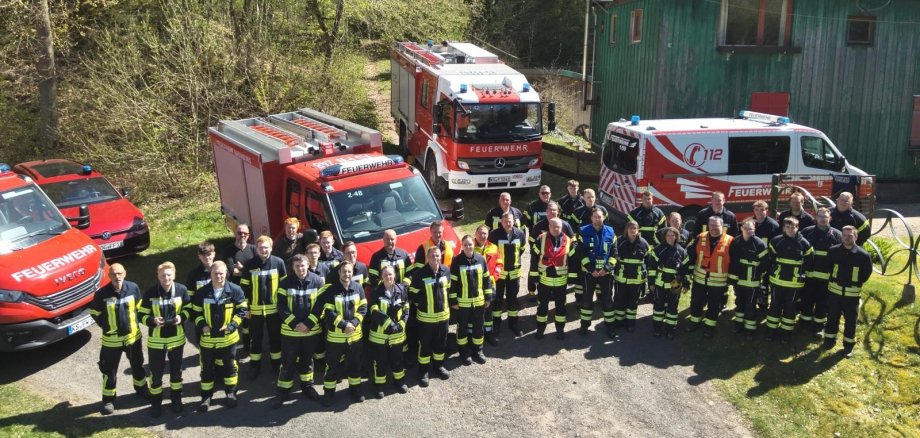 Feuerwehrfrauen und Feuerwehrmänner vor Feuerwehrfahrzeugen