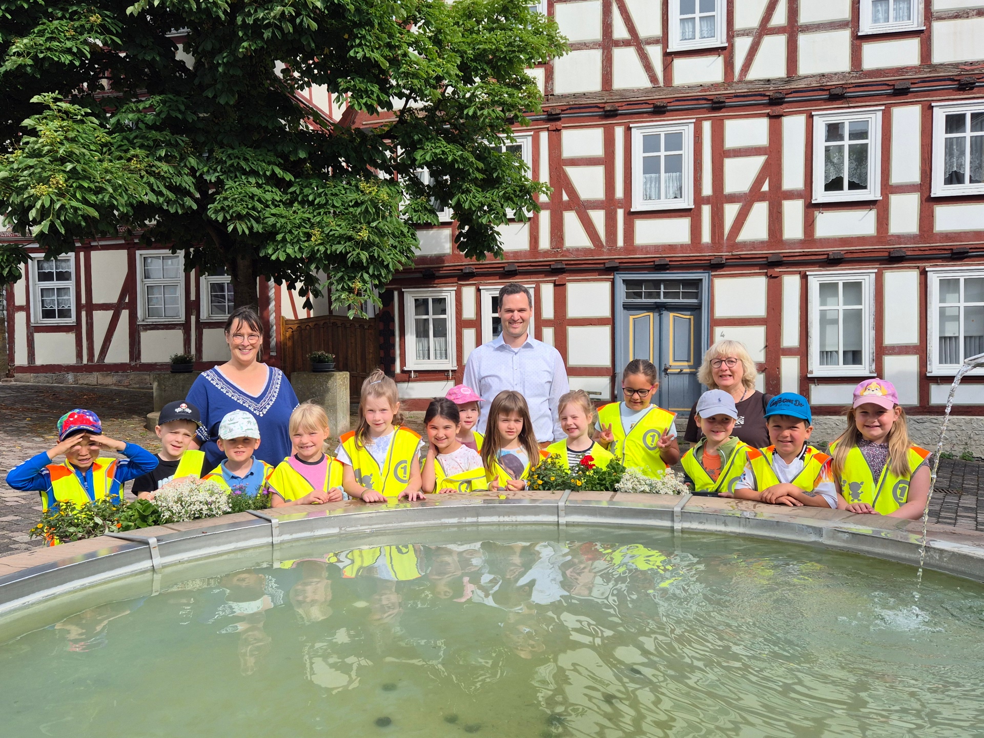 Kinder stehen an einem Brunnen der mit Wasser gefüllt ist