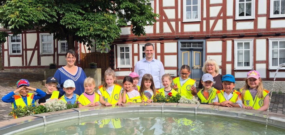 Kinder stehen an einem Brunnen der mit Wasser gefüllt ist