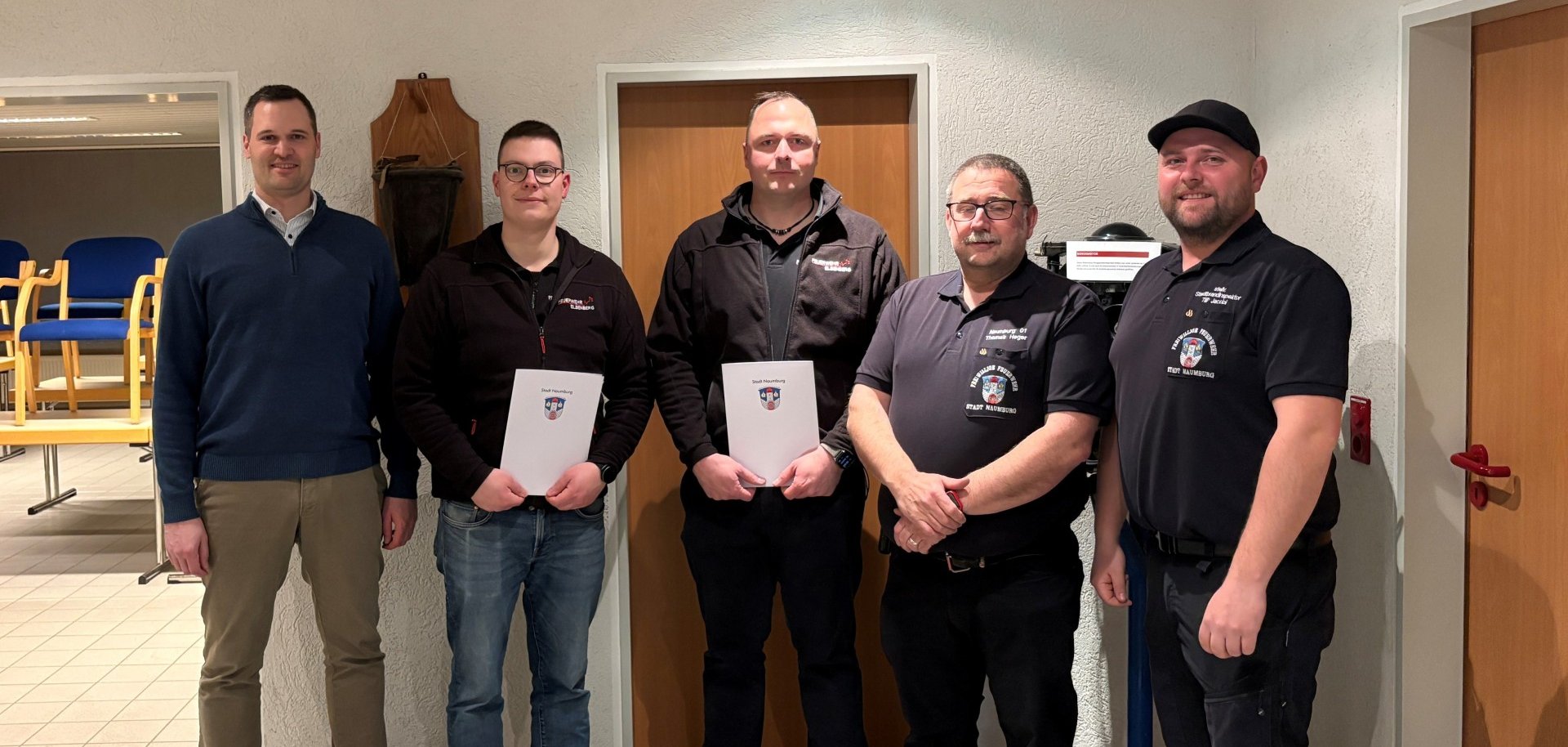 Bürgermeister, Wehrführer, Stadtbrandinspektor stehen vor einer Wand