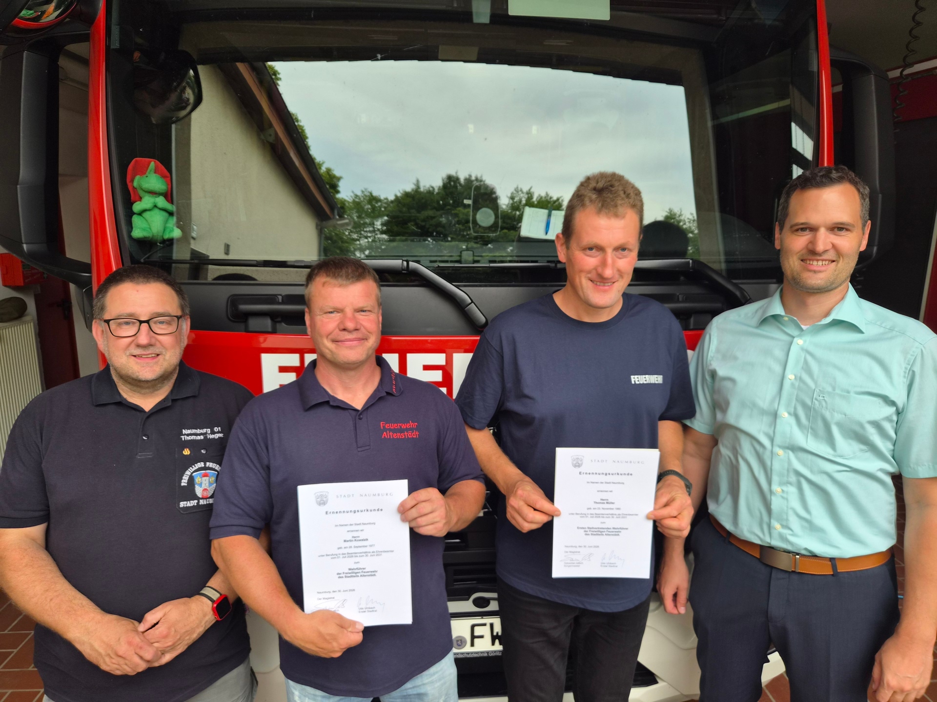 Vier Personen stehen vor einem Feuerwehrauto