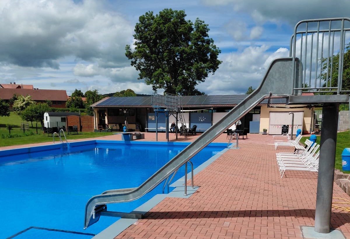Schwimmbad und im Vordergrund eine Rutsche die ins Wasser führt