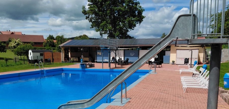 Schwimmbad und im Vordergrund eine Rutsche die ins Wasser führt