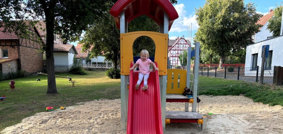 Kletterturm Rutsche Mädchen Rasen Bäume Sand Häuser Sandspielzeug